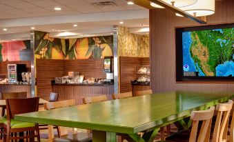 a dining area with a long green table and chairs , as well as a television mounted on the wall at Comfort Suites Canton