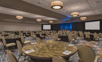 a large , empty conference room with round tables and chairs , surrounded by blue walls and black curtains at Sheraton Austin Georgetown Hotel & Conference Center