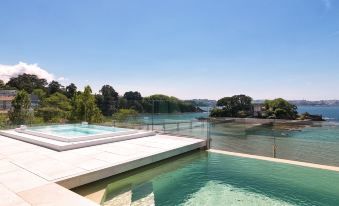 a modern house with a large pool and a hot tub overlooking a body of water at Noa Boutique Hotel