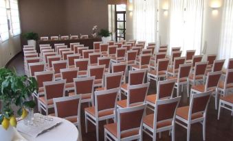 a conference room set up for a meeting , with rows of chairs arranged in a semicircle and a podium at Hotel Cavaliere