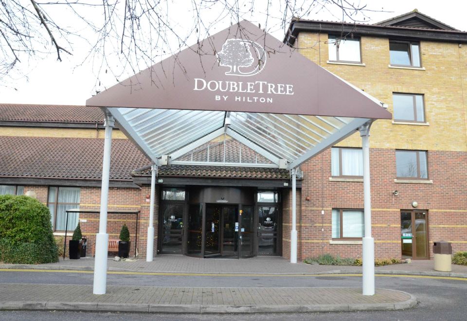 the entrance of a doubletree by hilton hotel , with its name displayed on a brown awning at DoubleTree by Hilton Swindon