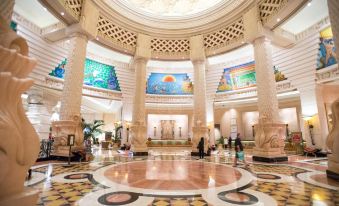 a large , ornate lobby with a circular reception area and a mural on the wall at The Royal at Atlantis