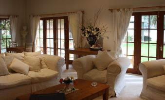 a cozy living room with a couch , chairs , and a dining table in front of a window at Strathearn Park Lodge