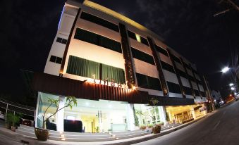 a nighttime scene of a large building , possibly a hotel or a restaurant , situated on a street at White Inn Nongkhai Hotel