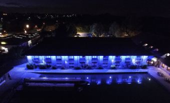 a building with blue lights on , lit up by the night sky , and surrounded by trees at Peartree Lodge Waterside