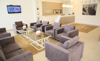 a large , modern waiting room with multiple couches and chairs arranged in an orderly fashion at Hotel Leone