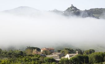 a picturesque village surrounded by fog , with a castle perched on top of a mountain in the background at Albergo Posta Marcucci