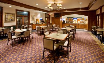 a large dining room with multiple tables and chairs , a buffet table , and a television at Holiday Inn & Suites Dallas-Addison