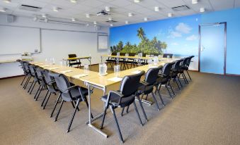 a large conference room with a long table and numerous chairs arranged for a meeting at Scandic the Reef
