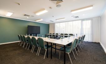 a conference room with a long table surrounded by chairs and a large screen on the wall at Quest Cannon Hill