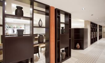 a room with brown furniture and shelves , an orange wall , and various decorative items on the shelves at Hotel Nord