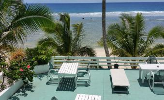 a balcony overlooking the ocean , with several lounge chairs and a table set up for relaxation at Paradise Inn