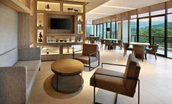 a modern living room with various seating options , including couches , chairs , and a coffee table at Royal Tulip Golf Resort Gunung Geulis