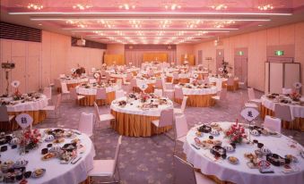 a large banquet hall filled with round tables and chairs , all set up for a formal event at Todaya