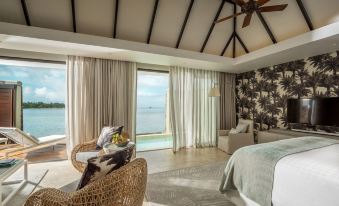 a luxurious bedroom with a view of the ocean , featuring a comfortable bed , a chair , and a television at Four Seasons Resort Mauritius at Anahita