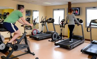 a group of people working out in a gym , with various exercise equipment including treadmills and stationary bikes at Aqua Hotel