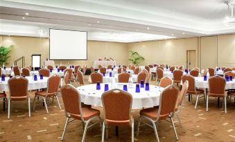 a large conference room with multiple round tables and chairs , ready for a meeting or event at Pelican Waters Resort