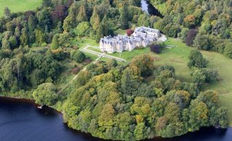 aerial view of a castle surrounded by lush green trees and a body of water at Glengarry Castle Hotel