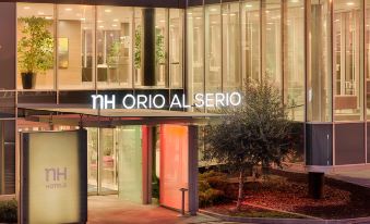 "a modern building with the sign "" nh orio al serio "" illuminated at night , and a tree in front" at NH Orio Al Serio