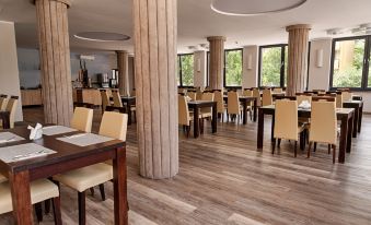 a large dining room with wooden floors , multiple tables , and chairs arranged for a group of people at Boutique Hotel's