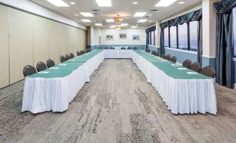 a long conference table with white linens and blue tablecloths is set up in a room at Ramada Plaza by Wyndham Nags Head Oceanfront