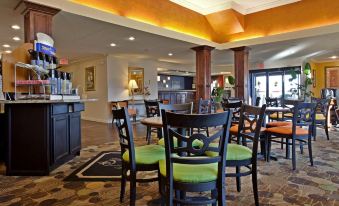a modern hotel lobby with a bar and dining area , featuring black tables and chairs at Spring Lake Inn & Suites - Fayetteville