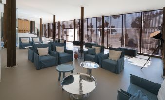 a modern living room with blue chairs and couches arranged around a coffee table , creating a comfortable seating area at Masseria Amastuola Wine Resort