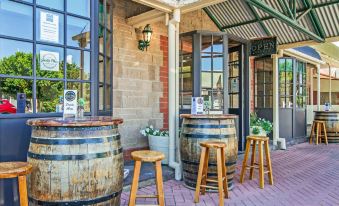 a brick building with wooden barrels and stools outside , where people are sitting and enjoying their time at Motel Goolwa