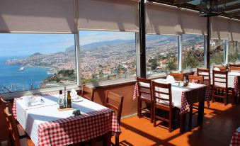 a restaurant with a view of the city , featuring red and white checkered tablecloths on tables and chairs at Ocean Gardens