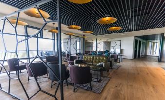 a modern office space with wooden floors , metal beams , and yellow ceiling lights , featuring multiple people sitting at desks and enjoying the view at Fosshotel Glacier Lagoon