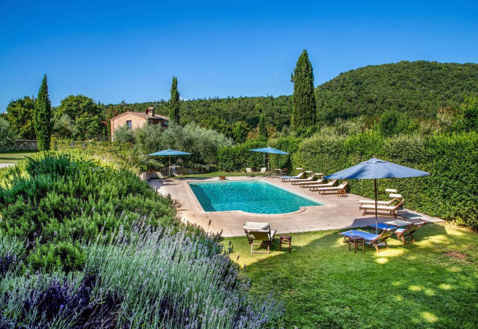 a large outdoor pool surrounded by lush green grass , with several lounge chairs and umbrellas placed around the pool area at Abbadia Sicille Relais