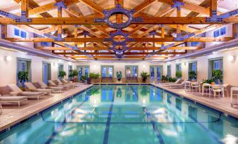a large indoor swimming pool surrounded by lounge chairs , with wooden beams hanging from the ceiling at The Equinox