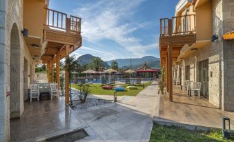 a resort with multiple buildings and a pool surrounded by a grassy area , mountains in the background at Dalyan Live Spa Hotel
