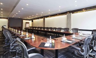 a large conference room with a long table , chairs , and various items on the table at Novotel Montreal Center