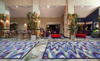 a hotel lobby with a large rug in the center , surrounded by chairs and couches at Holiday Inn Rock Springs