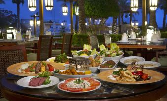 a dining table filled with a variety of dishes , including meat , vegetables , and other food items at InterContinental Hotels Aqaba (Resort Aqaba)