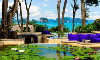 a serene outdoor setting with a large pool surrounded by lush greenery and a view of the ocean at Six Senses YAO Noi