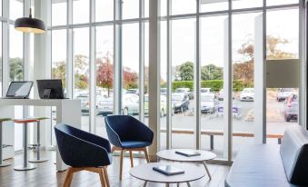a modern lounge area with two chairs , a coffee table , and a view of the outside at Ibis Budget Auckland Airport