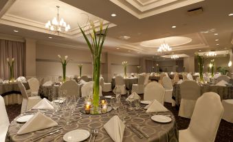 a large , well - decorated banquet hall with tables set for a formal event , featuring white tablecloths and silver decorations at Holiday Inn Laval - Montreal