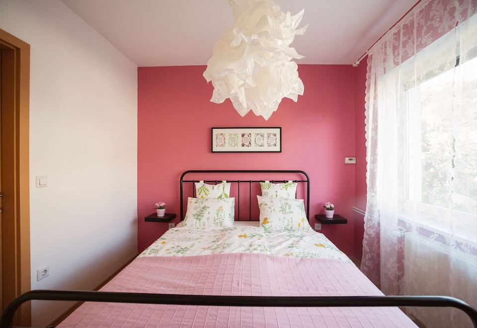 a pink bedroom with a double bed , a potted plant on the floor , and a tv mounted on the wall at Garden Apartment