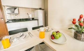 a kitchen with white cabinets , a sink , and a dining table with an orange juice and fruit at Verona Hplus Long Stay