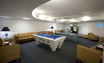 a large room with multiple tables , including a pool table , ping pong table , and couches at Mantra Mooloolaba Beach