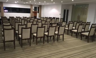 a large conference room with rows of chairs arranged in a semicircle , ready for a meeting or event at Gold Hotel