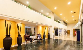 a modern building with yellow walls and white ceiling , two people sitting on couches in a lobby area at Best Western Plus Gran Hotel Morelia