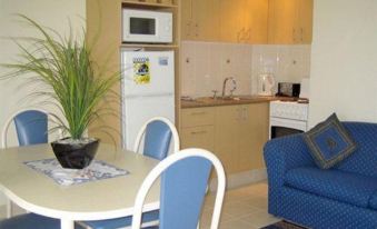 a kitchen and dining area with a blue chair , table , microwave , oven , sink , refrigerator , and cabinets at Bay of Palms