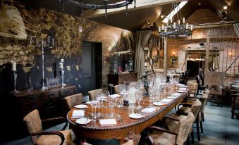 a dining room with a large wooden dining table surrounded by chairs , and a chandelier hanging above at The White Horse