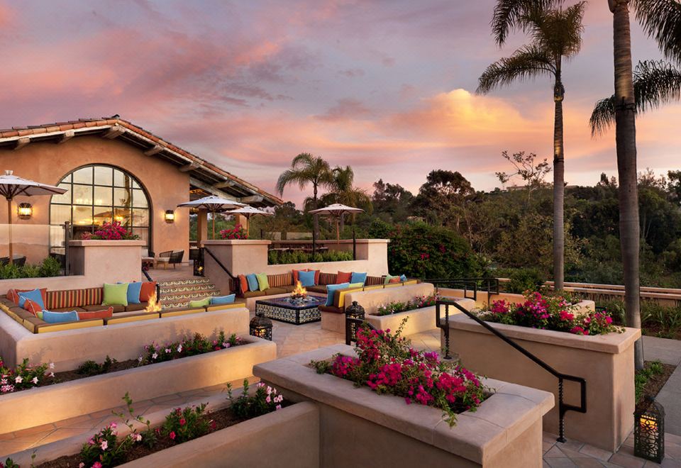 a beautiful outdoor patio area with a view of palm trees and a colorful couch at Rancho Valencia Resort and Spa
