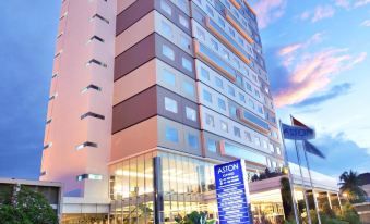 a tall building with a blue sign on the front , located in a city setting at Aston Kupang Hotel & Convention Center
