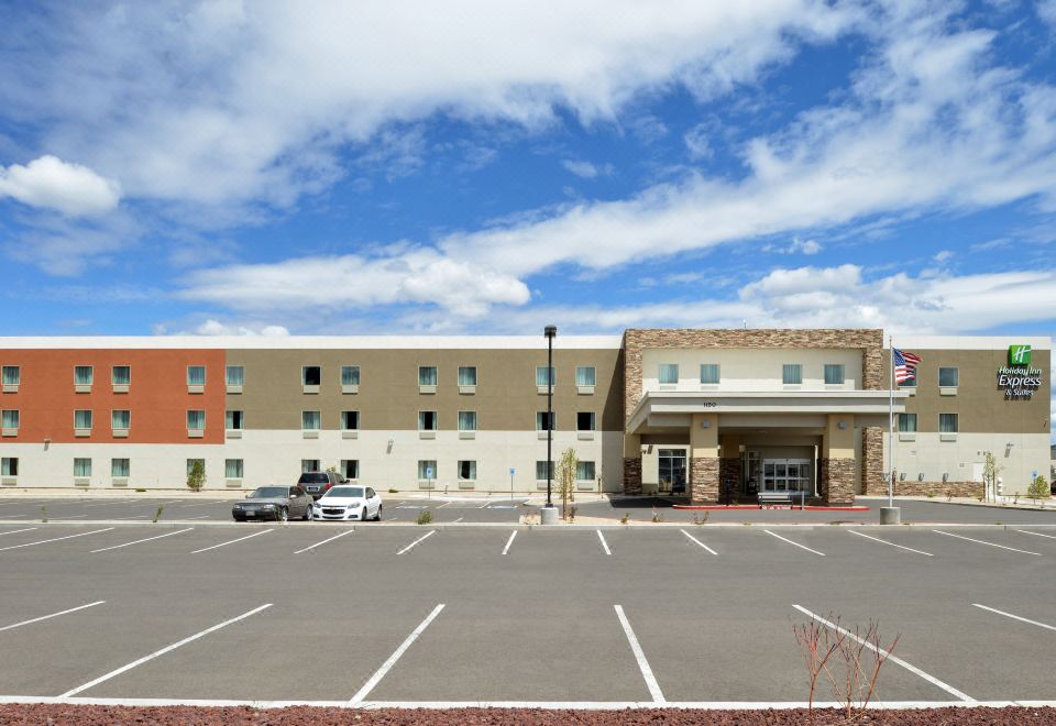 a parking lot with multiple cars parked in front of a building with a large window at Holiday Inn Express & Suites Williams