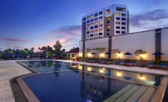 At night, there is a swimming pool in front of the hotel with sun loungers, and the building is illuminated at Aryaduta Bandung
